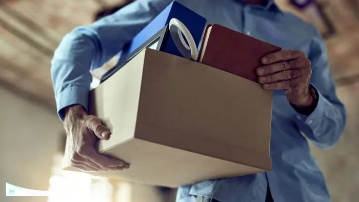 Foto ilustrasi ini menggambarkan seorang karyawan yang membawa kardus berisi barang-barang pribadinya seperti buku, bingkai foto, dan berkas kerja usai terkena pemutusan hubungan kerja (PHK).