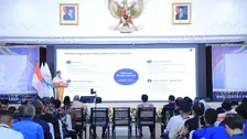 Menaker Yassierli berdiri di podium dan menyampaikan paparan di hadapan peserta seminar. Pada layar di belakangnya tampil slide berjudul Membangun Bersama Ekosistem Talenta. Slide itu memuat peran empat pihak, yakni industri, perguruan tinggi, asosiasi profesi, dan pemerintah/Kemnaker, dalam menyiapkan talenta masa depan yang kompeten, adaptif, tersertifikasi, dan siap kerja. Para peserta duduk menyimak paparan.