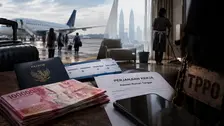 Kolase ilustrasi memperlihatkan sejumlah calon penumpang berjalan menuju pesawat di landasan bandara. Di bagian depan tampak paspor Indonesia, tiket dengan rute Waingapu, Pekanbaru, Tanjung Balai, dan Kuala Lumpur, serta setumpuk uang rupiah. Di sisi kanan terlihat siluet pekerja rumah tangga mengepel lantai dengan latar menara kembar di Kuala Lumpur, dokumen "Perjanjian Kerja Asisten Rumah Tangga", telepon seluler, dan papan bertuliskan "TPPO" yang dililit rantai.