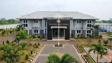 Tampak depan gedung dua lantai Lapas Kelas IIA Cibinong dengan papan nama "Lembaga Pemasyarakatan IIA Cibinong", halaman berpaving, tiang bendera, dan taman di sekelilingnya.