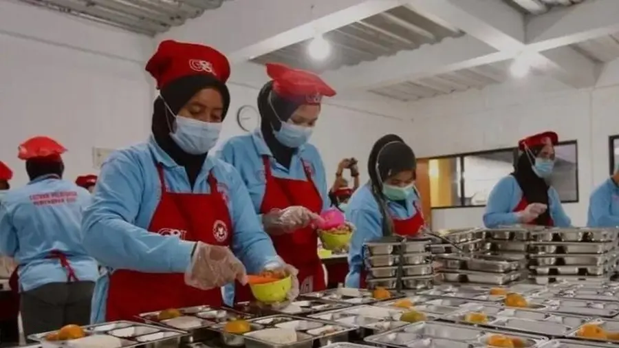 Suasana aktivitas pekerja dalam proses penyiapan dan distribusi makanan bergizi di dapur umum program MBG Suasana aktivitas pekerja dalam proses penyiapan dan distribusi makanan bergizi di dapur umum program MBG