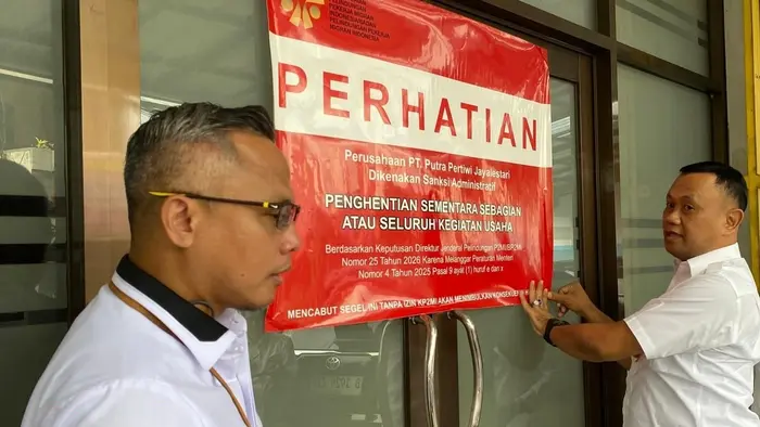 Petugas KP2MI memasang plang peringatan berwarna merah di pintu kantor PT Putra Pertiwi Jayalestari sebagai tanda pemberlakuan sanksi administratif.