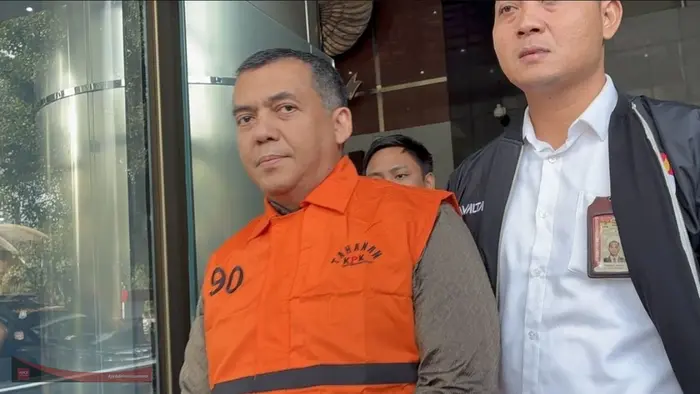 Silmy Karim mengenakan rompi tahanan oranye KPK nomor 90 berjalan keluar dari Gedung Merah Putih KPK dengan ekspresi tegang menghadap ke arah kamera