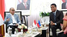 Foto menampilkan momen pertemuan antara Duta Besar Filipina Christopher B. Montero yang duduk di sisi kiri mengenakan setelan jas biru muda sambil memegang lembaran dokumen, berbincang dengan Menteri P2MI Mukhtarudin yang duduk di sisi kanan mengenakan jas gelap dengan dasi bermotif garis.