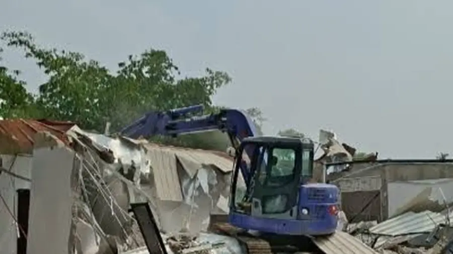 Pemkab Bogor: Lahan "Apartemen" Lapas Cibinong Tetap Aset Daerah Ekskavator biru membongkar bangunan beratap seng dengan puing yang berserakan di sekitarnya. Di latar belakang tampak pepohonan dan langit berawan.